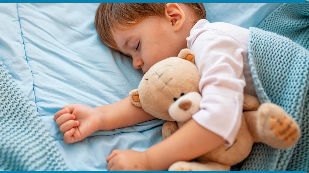 Bebê dormindo abraçado com um urso de pelúcia