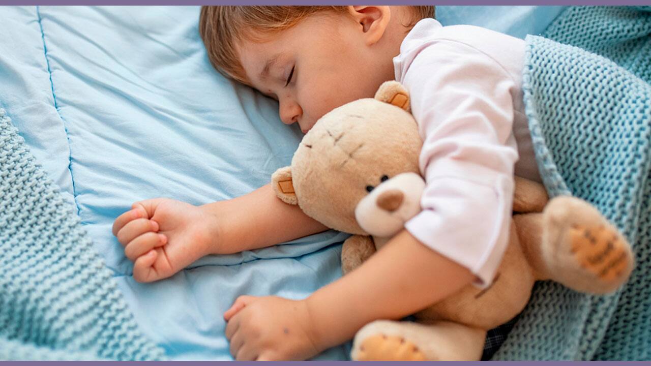 Bebê dormindo no berço abraçado a um urso de pelúcia