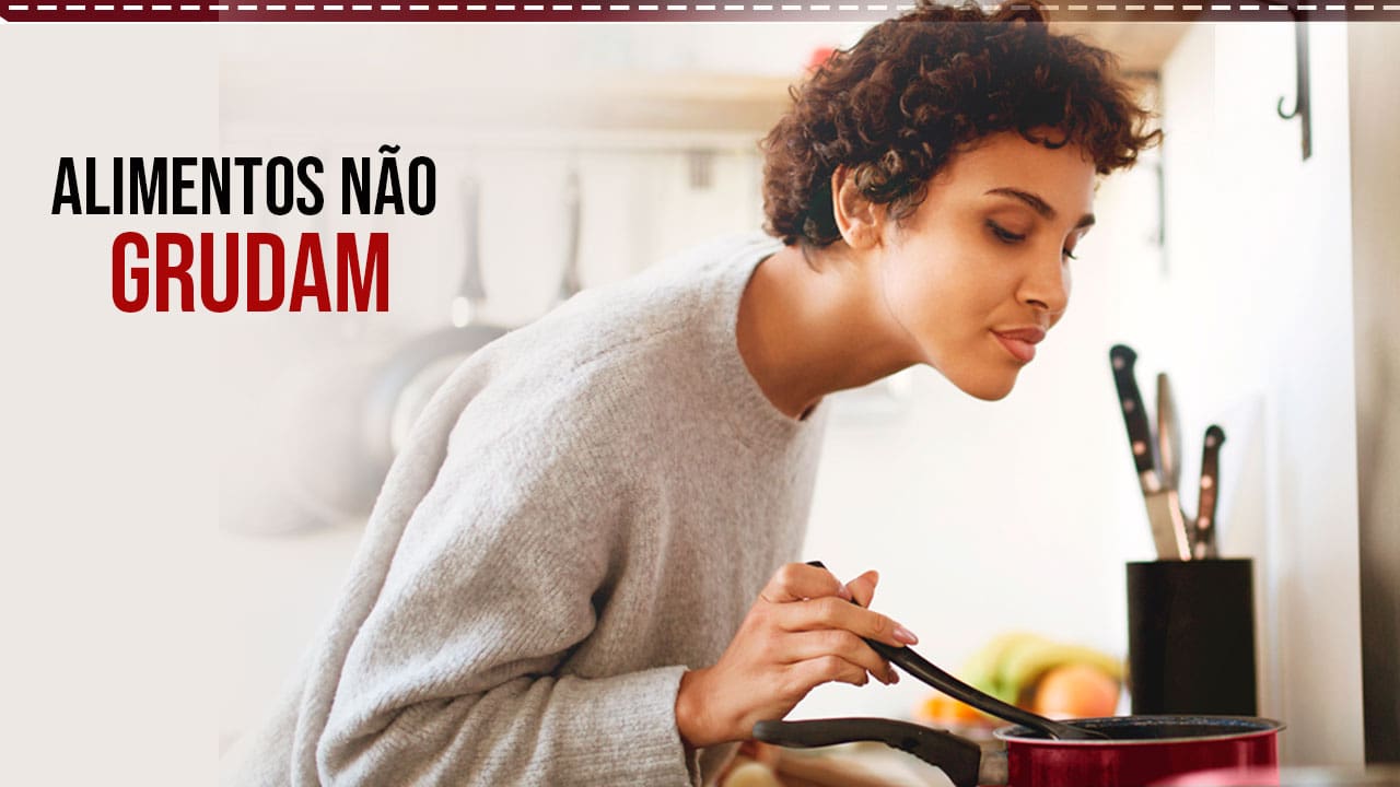 alimentos não grudam mulher moça jovem morena cabelo curto olhando panela preparo alimento fundo facas frigideiras penduradas