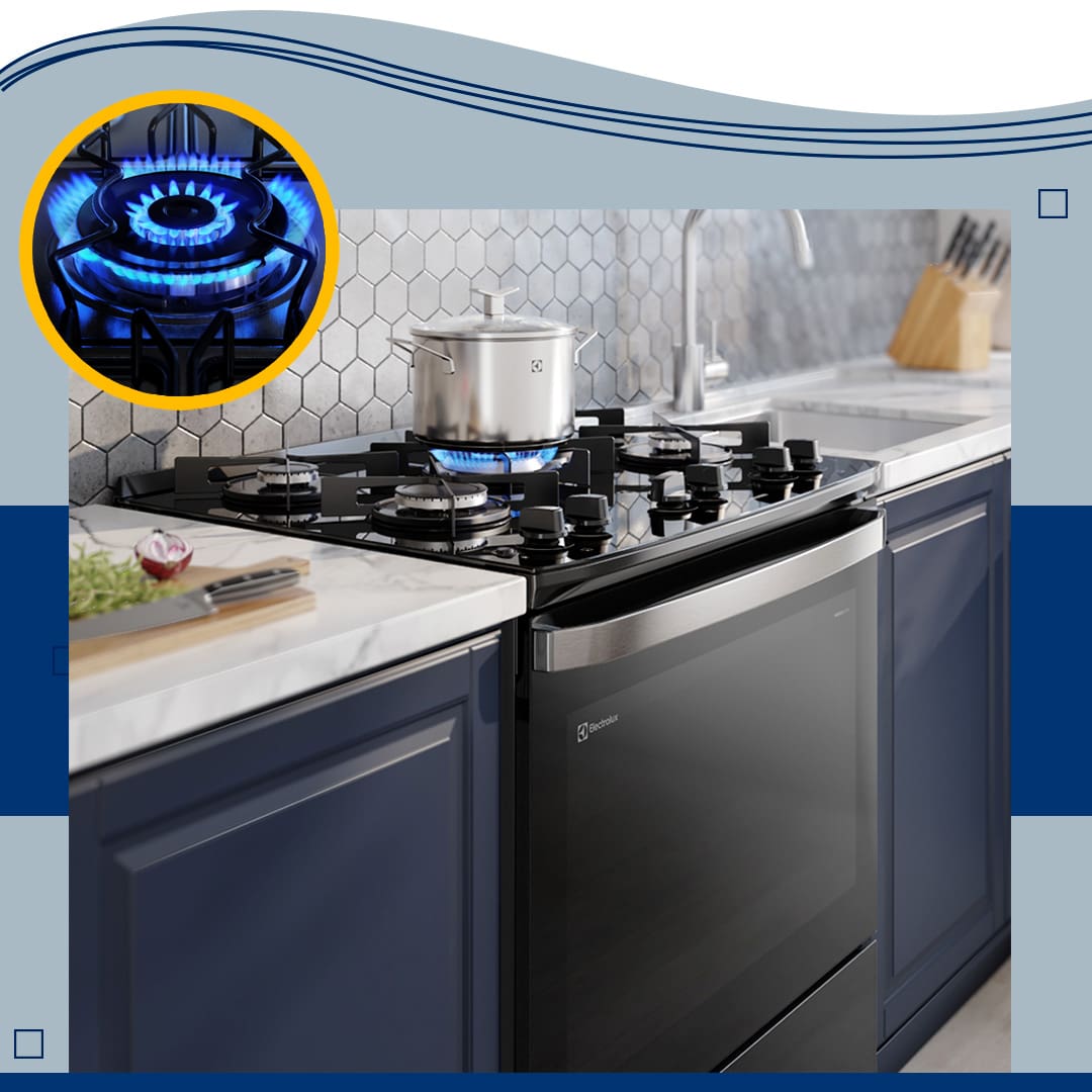imagem frontal frente aproximada destaque zoom boca acesa queimador ligado Fogão Electrolux preto cinza prata panela fogo aceso faca tábua madeira verdura verde torneira pia armário preto azul tampo mármore branco parede decorada