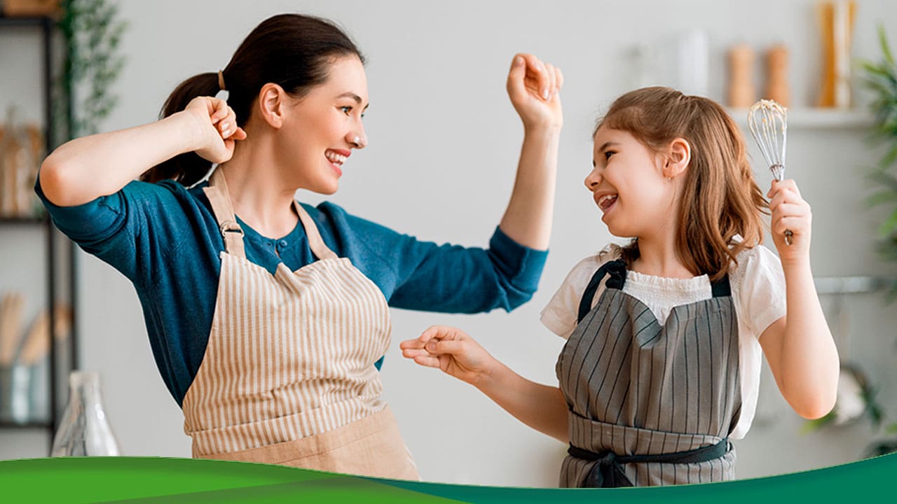 Mãe e filha com aventais e divertindo na cozinha