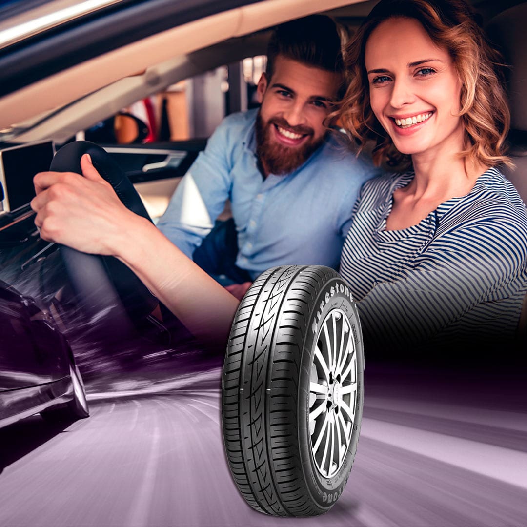 imagem mostra homem e mulher no carro e o pneu em primeiro plano na imagem