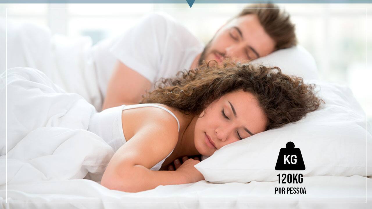 imagem mostra um casal dormindo em uma cama confortável com lençóis e travesseiros brancos