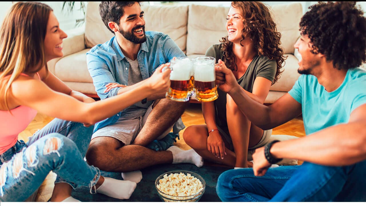 Quatro pessoas sentadas no chão, brindando com canecas de chopp
