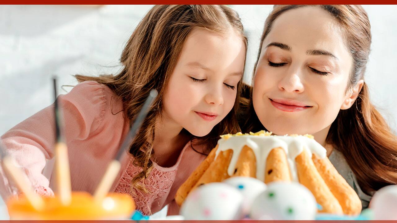 Mãe e filha de frente para um bolo