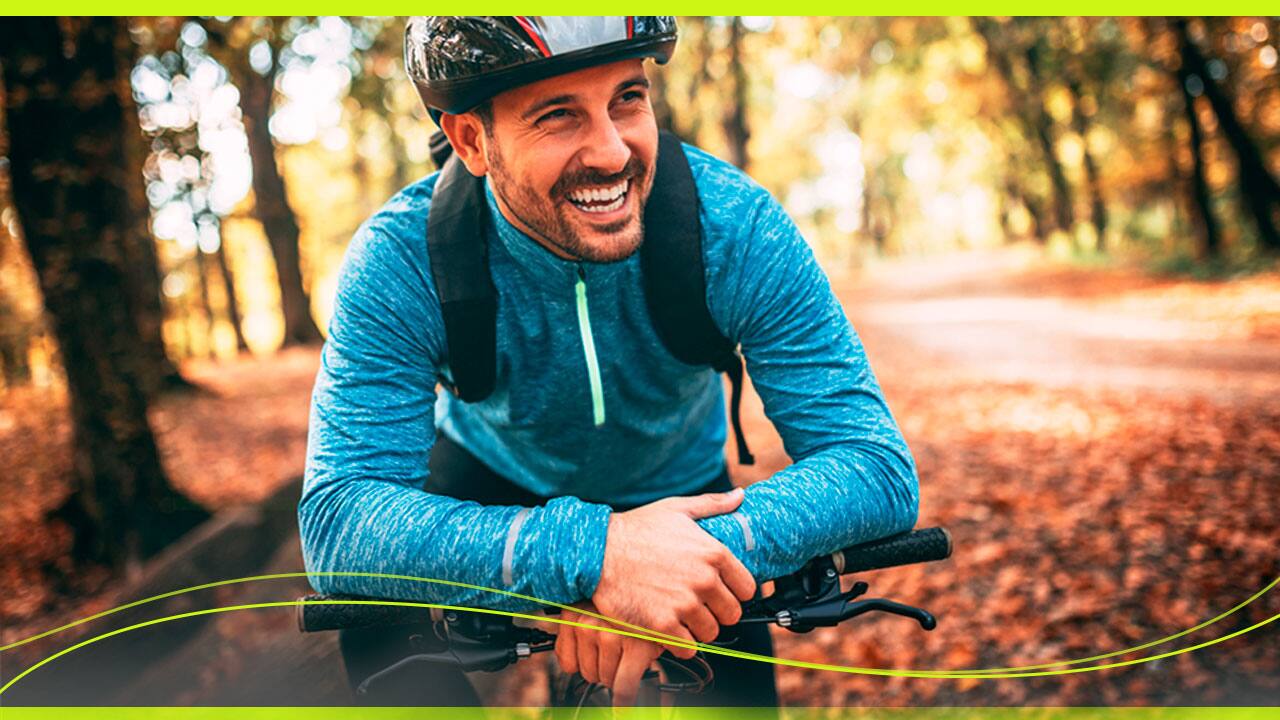 Ciclista sorridente, com mochila e capacete, sobre a Bike Houston Foxer Hammer 