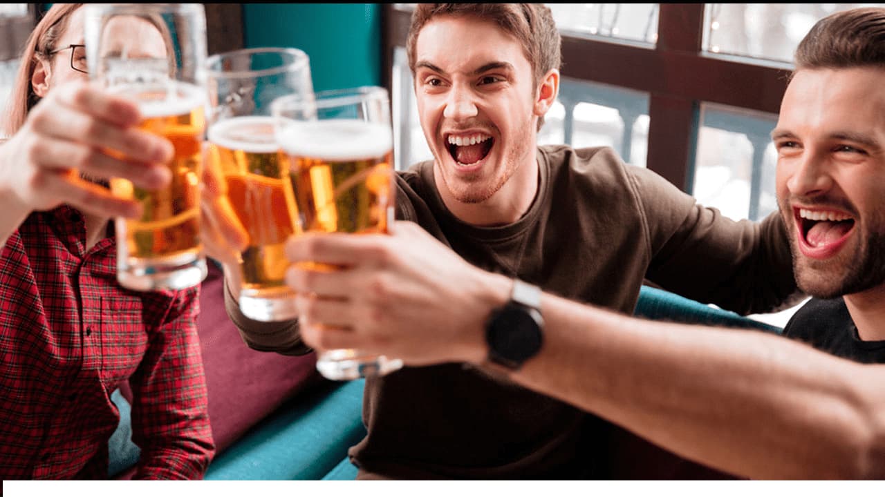 Três pessoas brindando com copos de cerveja