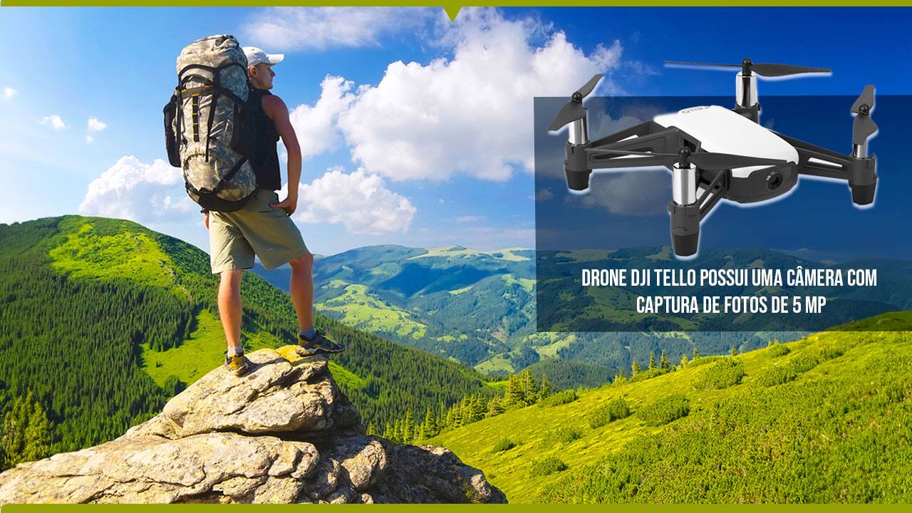Drone DJI Tello possui uma câmera com captura de fotos de 5 MP imagem equipamento branco preto fundo homem moço rapaz mochileiro chapéu boné camiseta regata bermuda tênis sobre pedra alto observando natureza área montanhosa montanhas árvores vale vegetação verde céu azul nuvens brancas sol calor  
