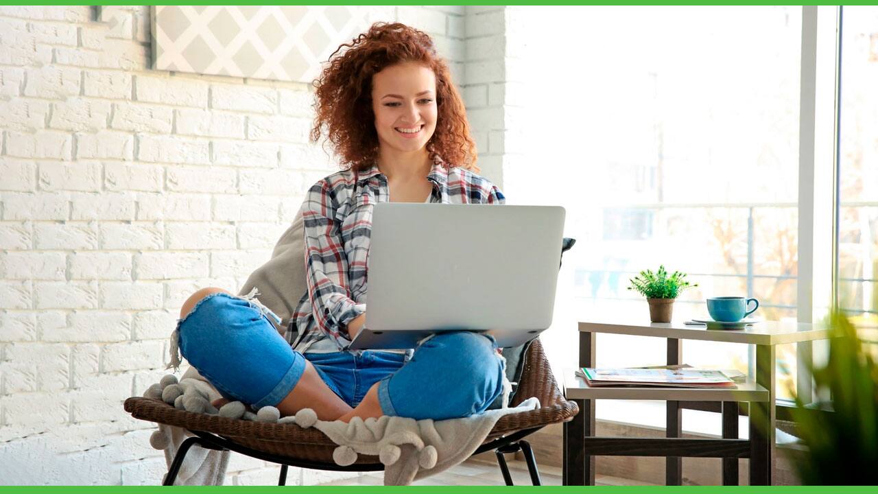 Mulher sentada na poltrona usando o notebook