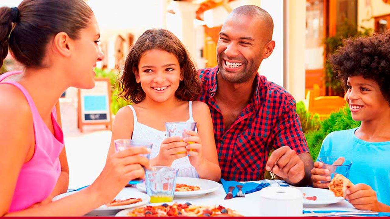 Pais e filhos na mesa de jantar comendo uma pizza