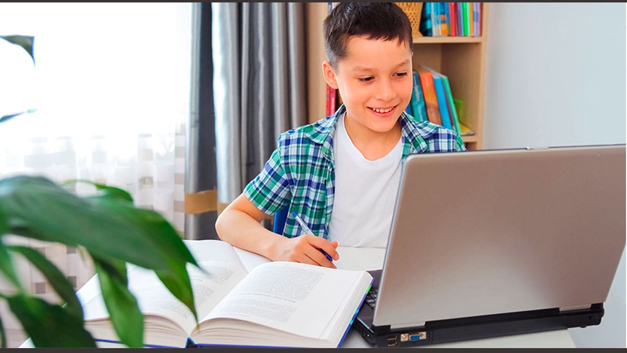 Garoto com livros e notebook sobre a mesa