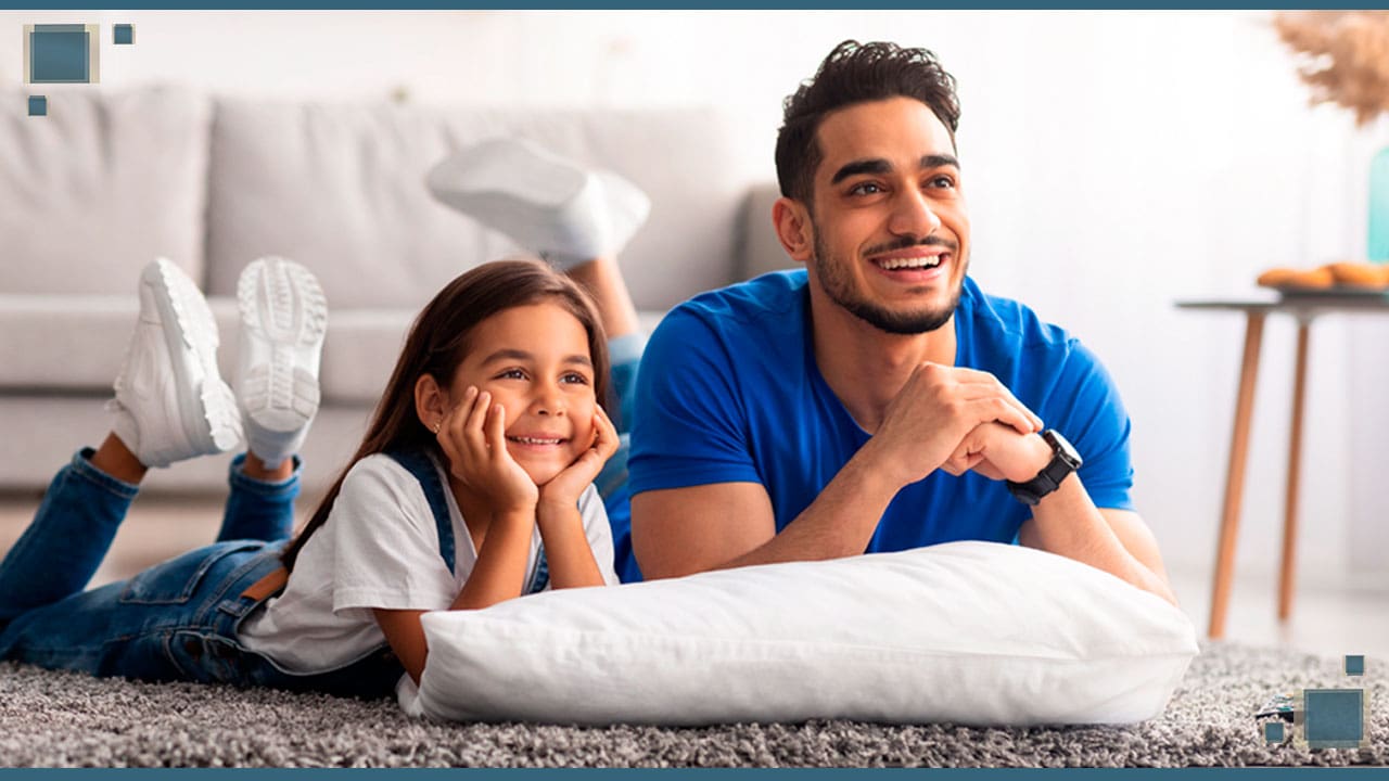 Pai e filha deitados no tapete assistindo TV