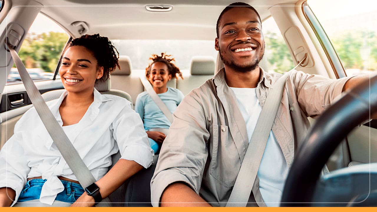 família preta negra pretos negros dentro carro interior veículo homem marido jovem moço dirigindo direção volante mulher esposa jovem moça criança menina garota atrás banco traseiro rindo sorrindo sorrisos alegres alegria