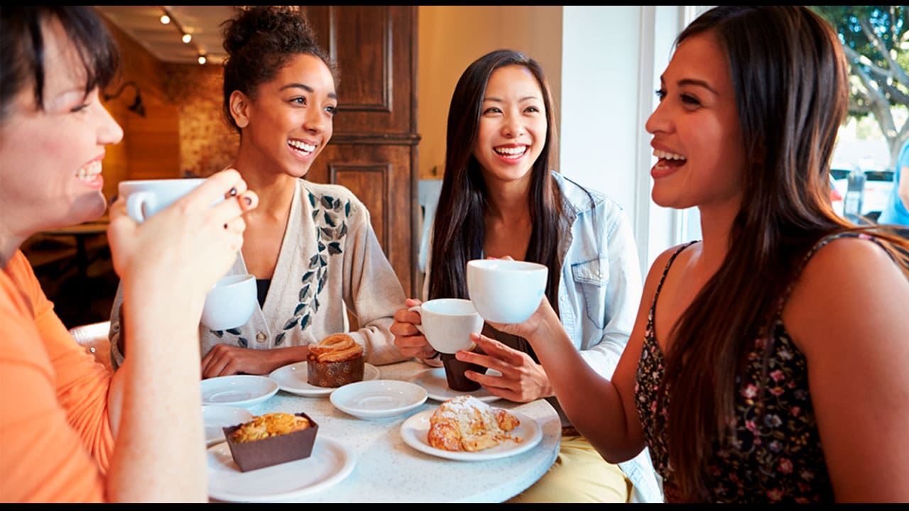 Quatro amigas reunidas cobre a mesa, tomando café