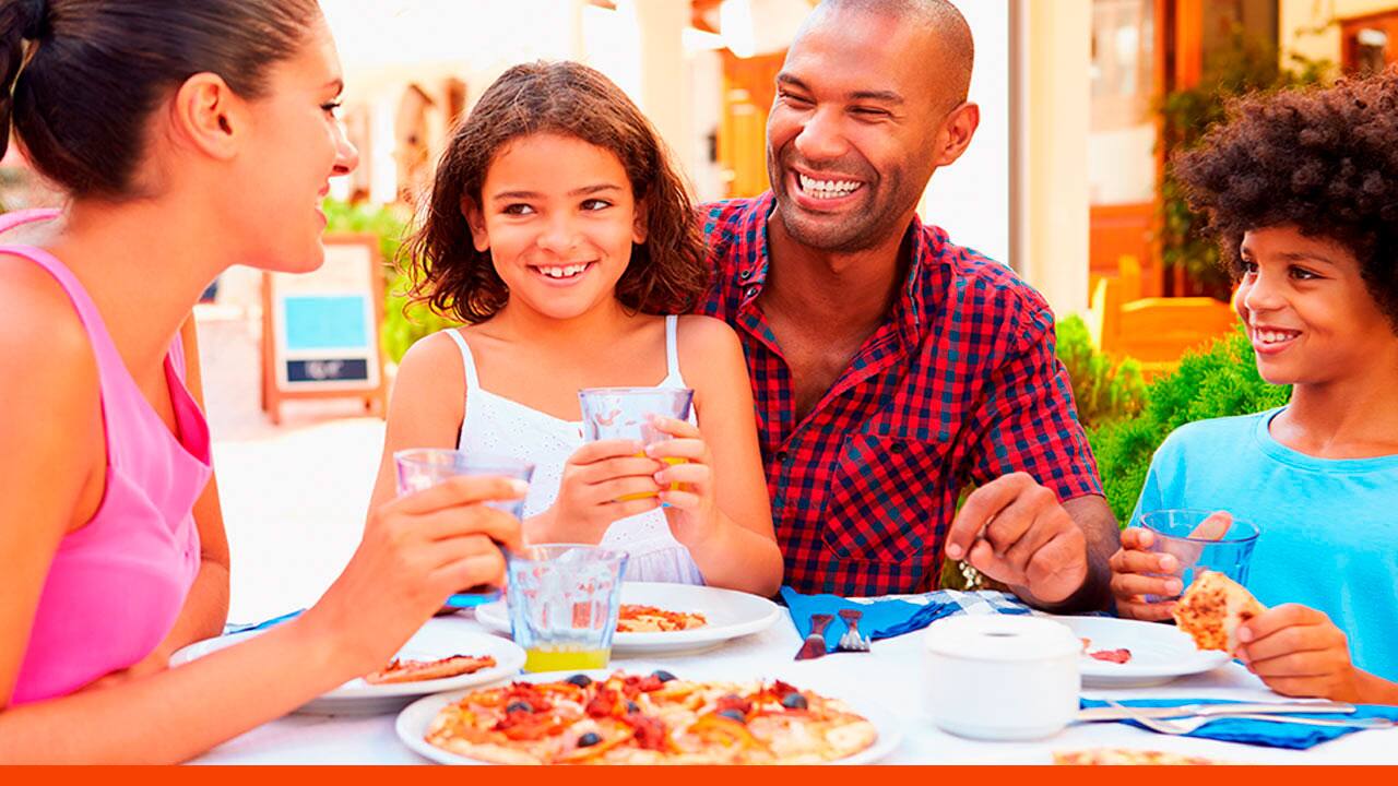 Pais e filhos na mesa de jantar comendo uma pizza