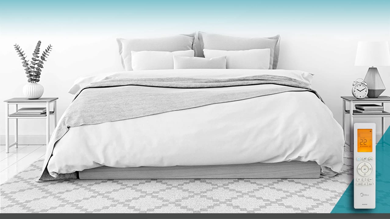 Imagem frontal frente cama branca cinza travesseiros coberta cobertor controle remoto branco painel luz laranja mesas pequenas vaso flor relógio despertador abajur livros tapete arte desenho formato geométrico