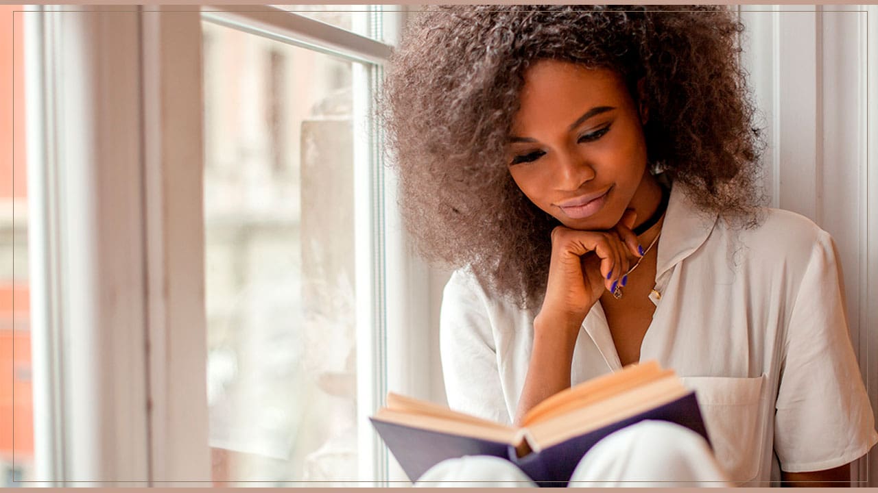 Mulher lendo um livro perto da janela