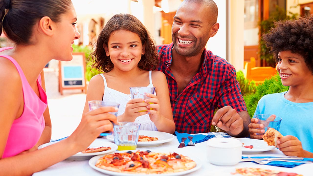 Pais e filhos na mesa de jantar comendo uma pizza