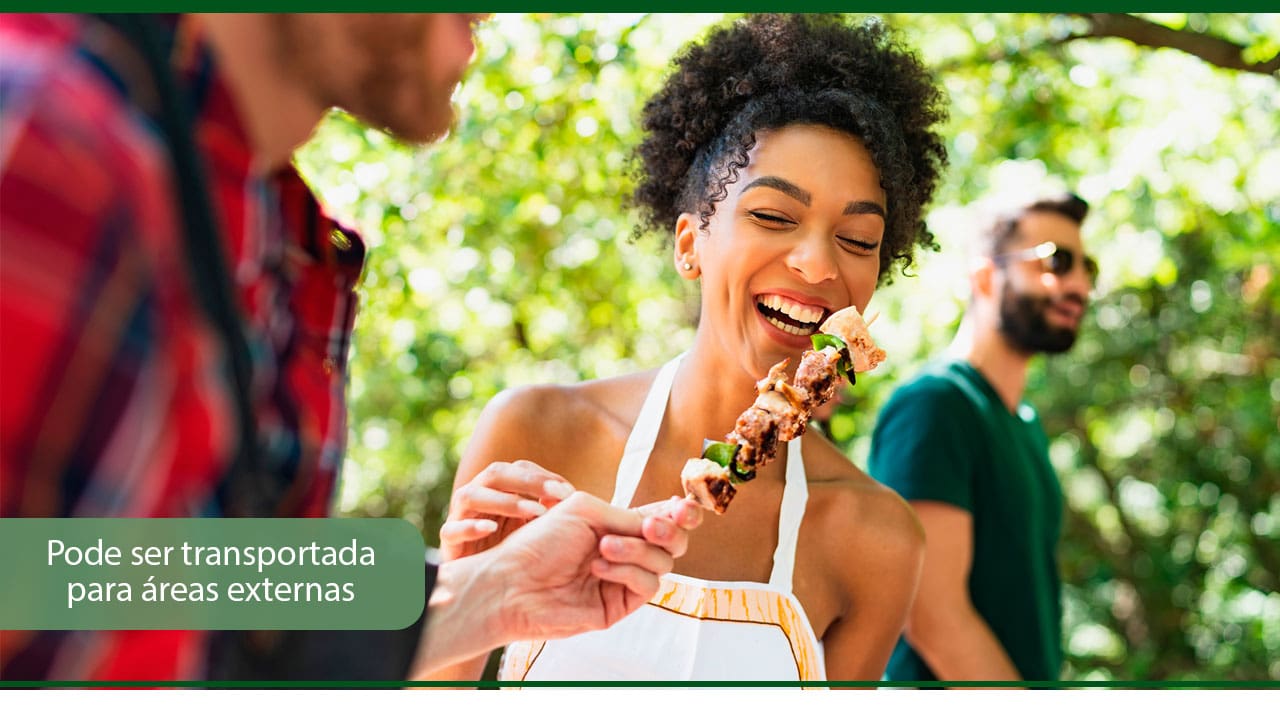 pode ser transportada para áreas externas imagem mulher moça jovem negra mulata avental sorrindo moços homens jovens brancos sorriso óculos de sol espeto churrasco carne árvores verde natureza